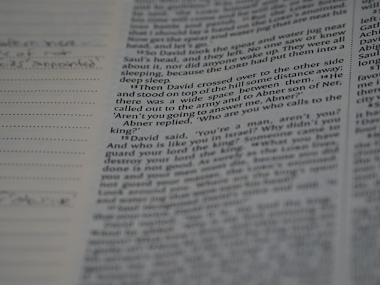A close-up view of a page from a book, featuring printed text with some handwritten notes in the margins on the left side.