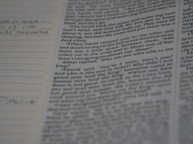 A close-up view of a page from a book, featuring printed text with some handwritten notes in the margins on the left side.