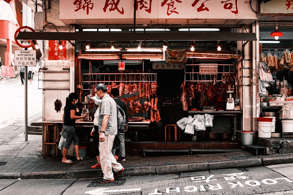 man in white dress shirt and white pants standing beside store during daytime