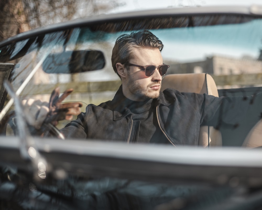 man in black sunglasses driving car