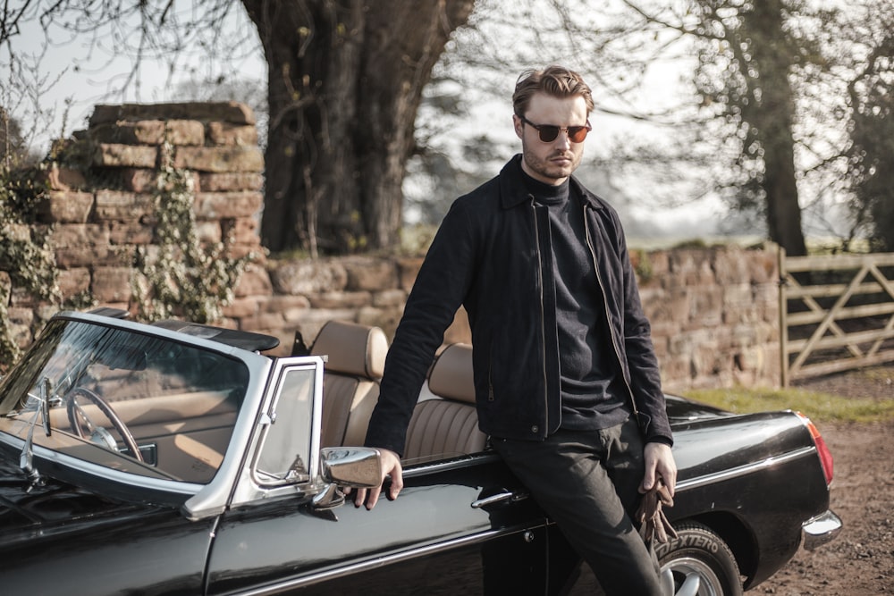 man in black jacket sitting on black car