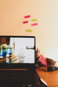 A creative workspace with a laptop displaying regulatory flowcharts and notes pinned on a corkboard.