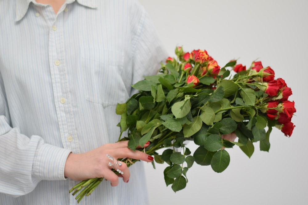 persona sosteniendo un ramo de rosas rojas