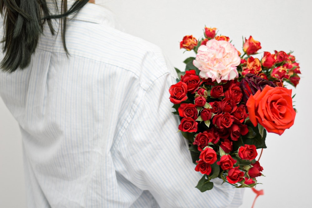 赤いバラを持った白い長袖シャツの女性