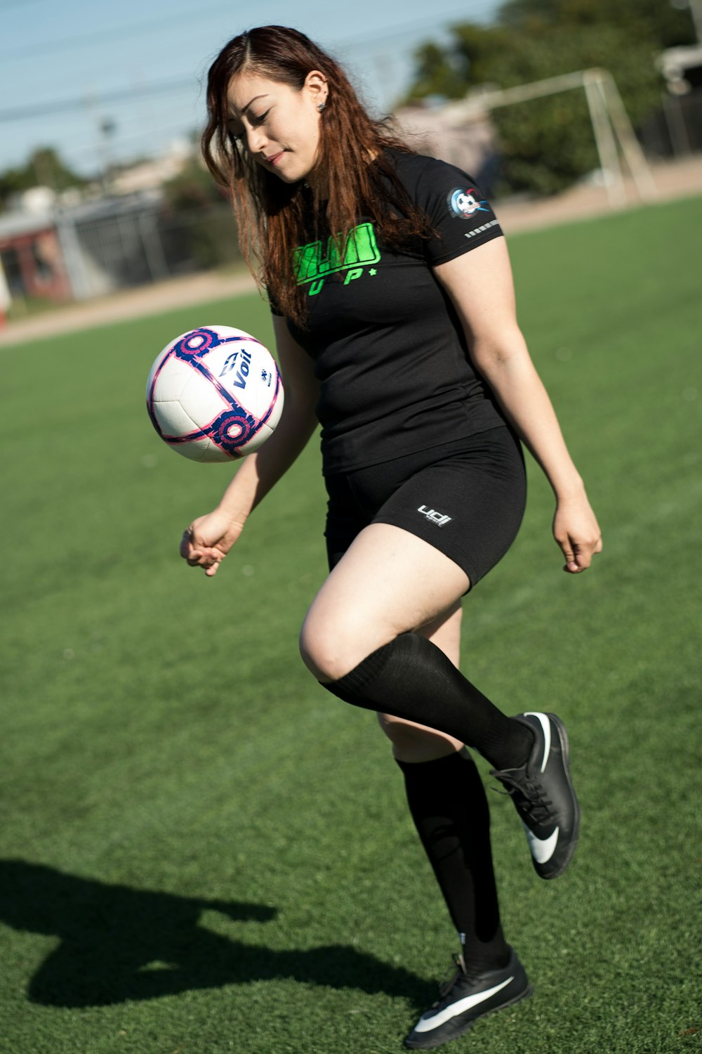 Foto mujer en camiseta de fútbol nike negra pateando una pelota de fútbol –  Imagen Soccergame gratis en Unsplash
