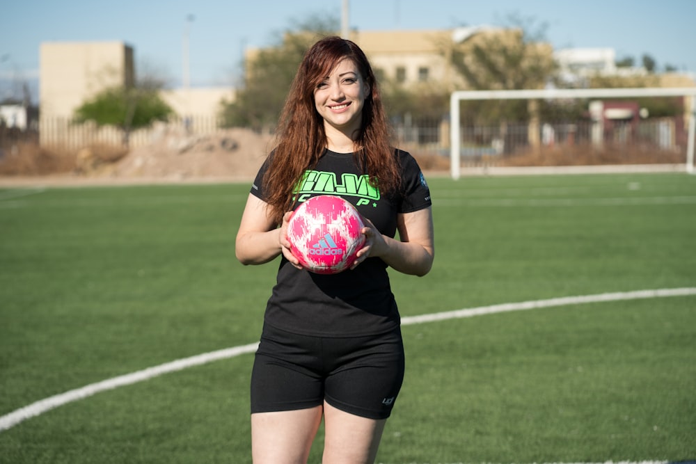 woman in black and pink nike soccer jersey shirt and black shorts holding pink ball