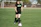 Close-up of a determined female footballer dribbling the ball on a green pitch.