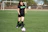 Close-up of a determined female footballer dribbling the ball on a green pitch.
