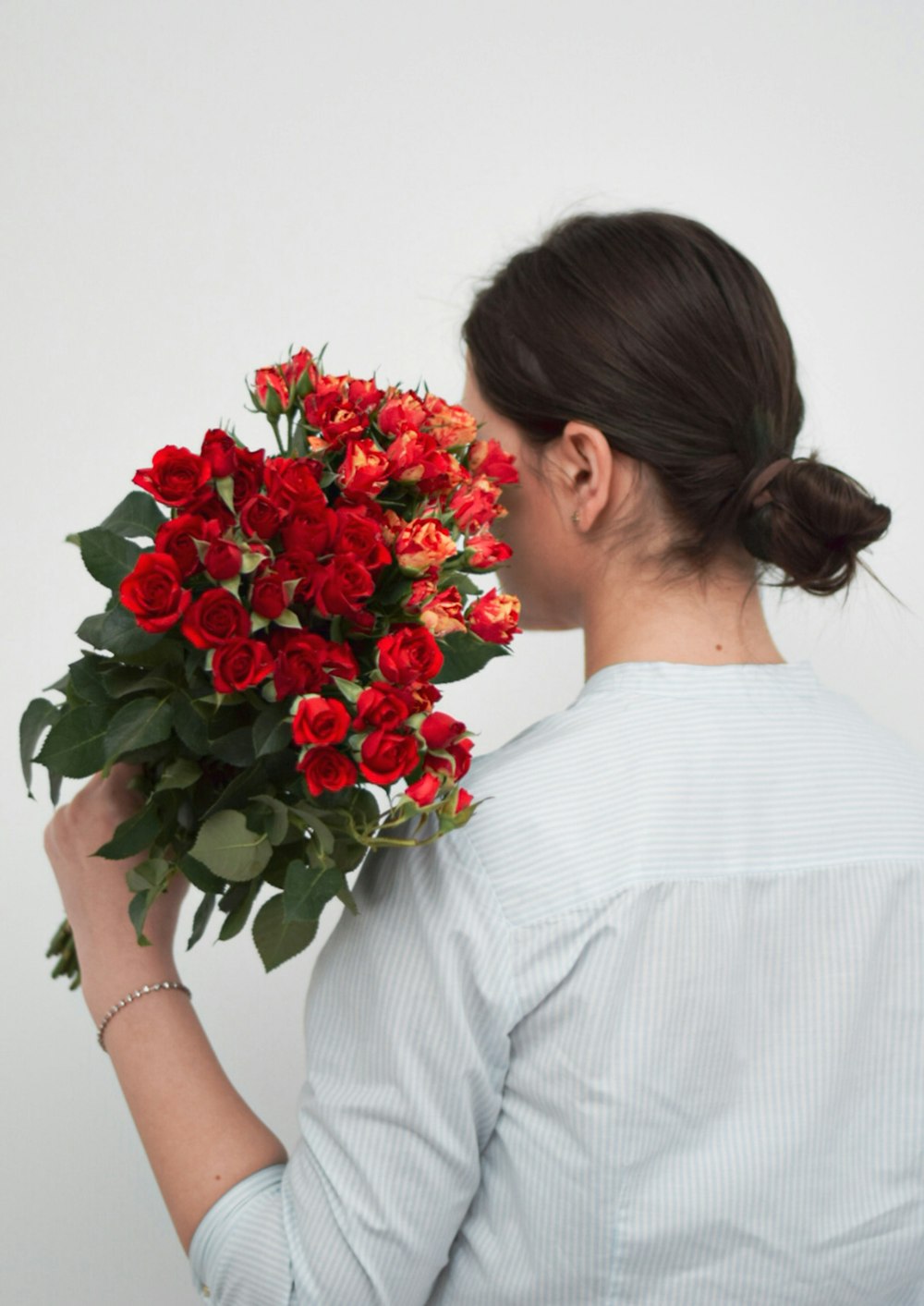 woman in white dress holding red roses