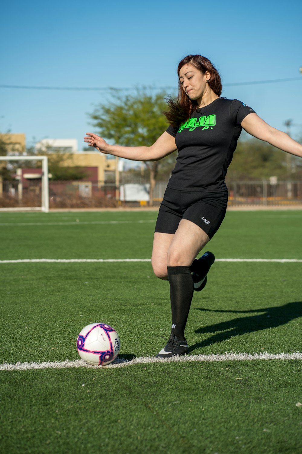 woman in black shirt and black shorts playing soccer during daytime
