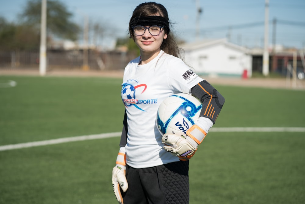 woman in white and blue nike soccer jersey shirt and black pants holding white and blue