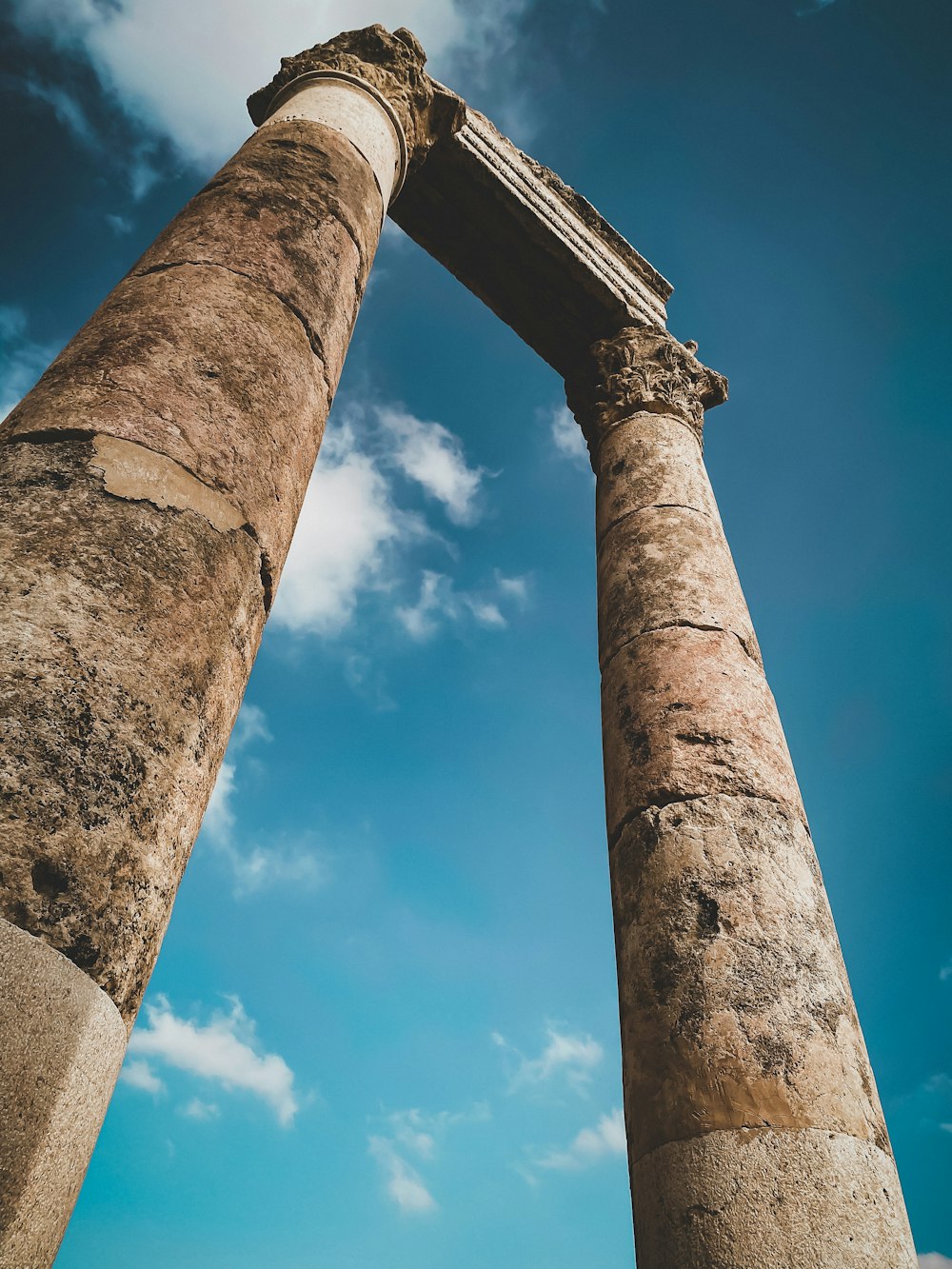 low angle photography of gray concrete post under blue sky during daytime