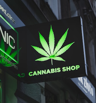 a cannabis shop sign hanging from the side of a building