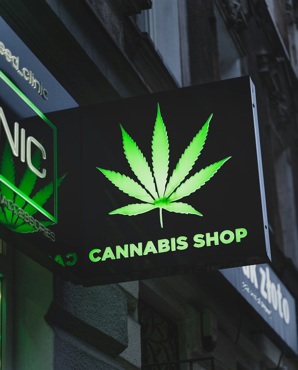 a cannabis shop sign hanging from the side of a building