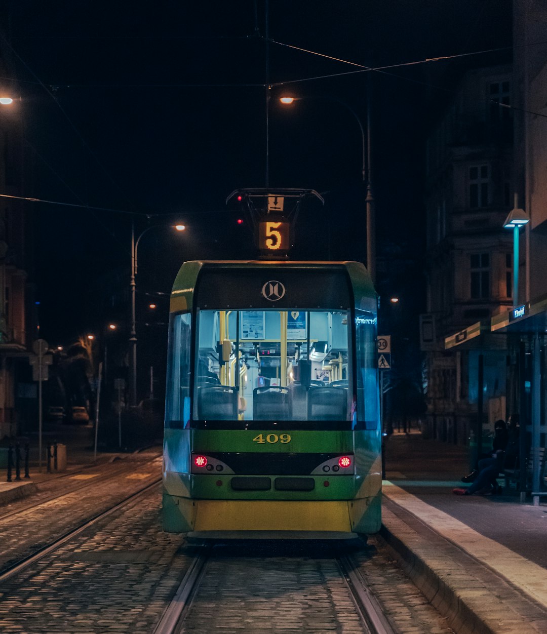 green and white tram on road during night time