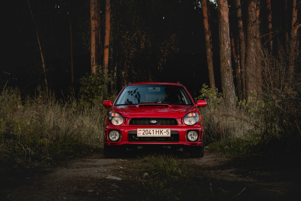 red bmw car parked beside brown tree