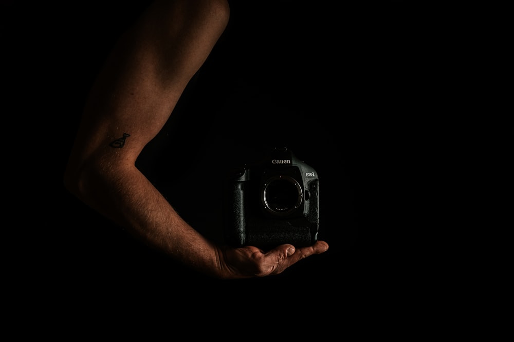 person holding black and silver camera