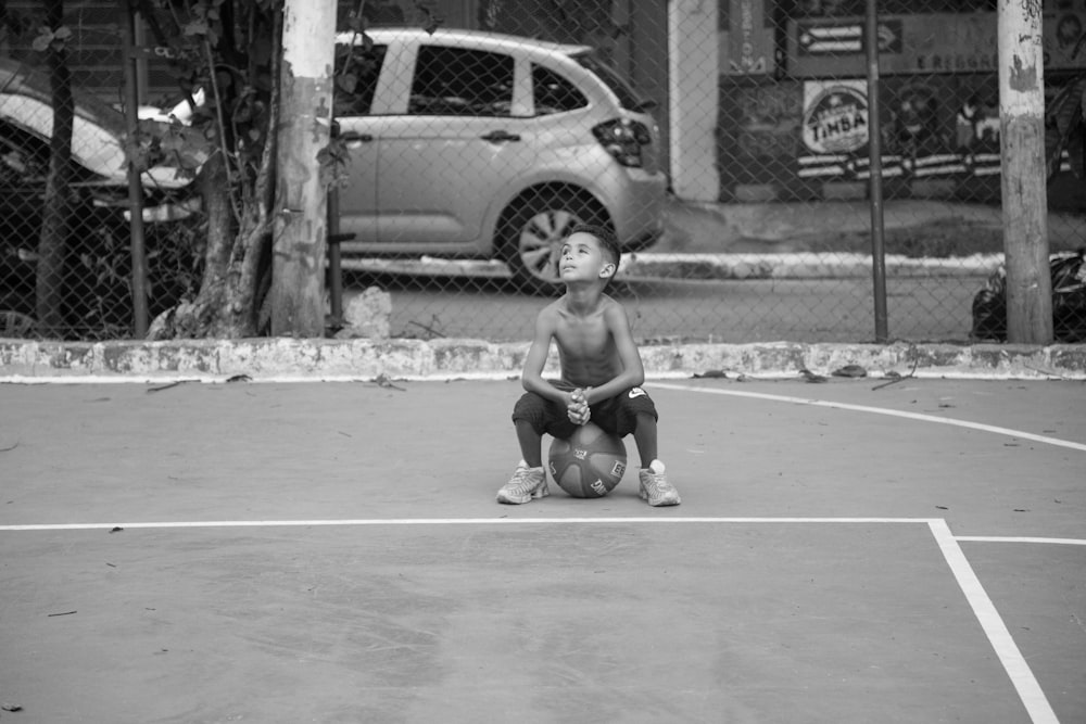 grayscale photo of child sitting on the ground