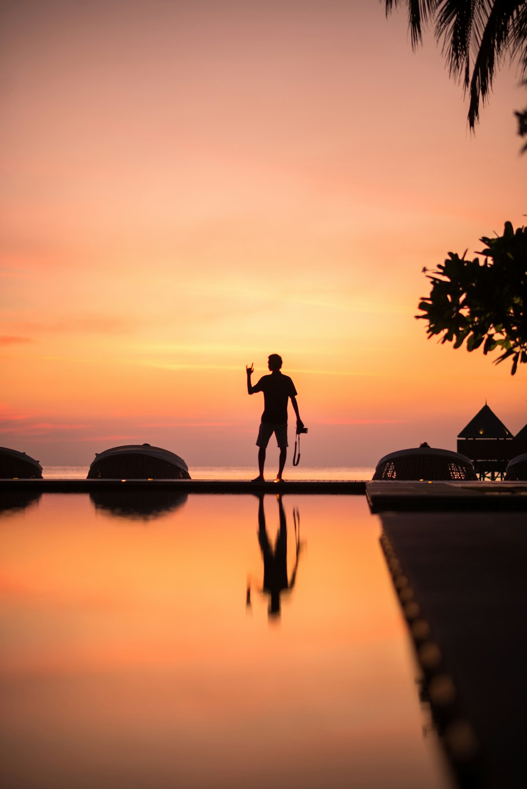 silhouette of man and woman standing on dock during sunset