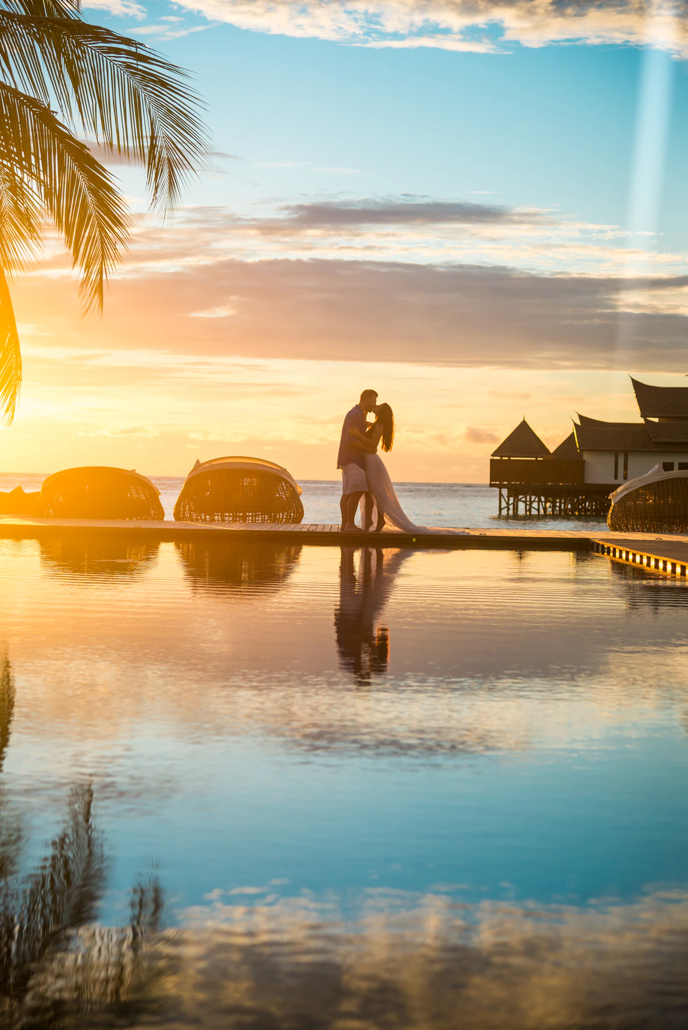 A couple embracing at sunset on an overwater deck