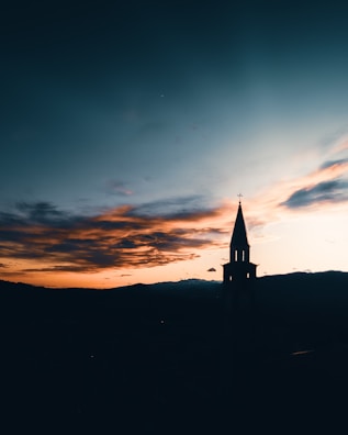 Artistic sketch of a church steeple silhouetted against a deep blue evening sky.