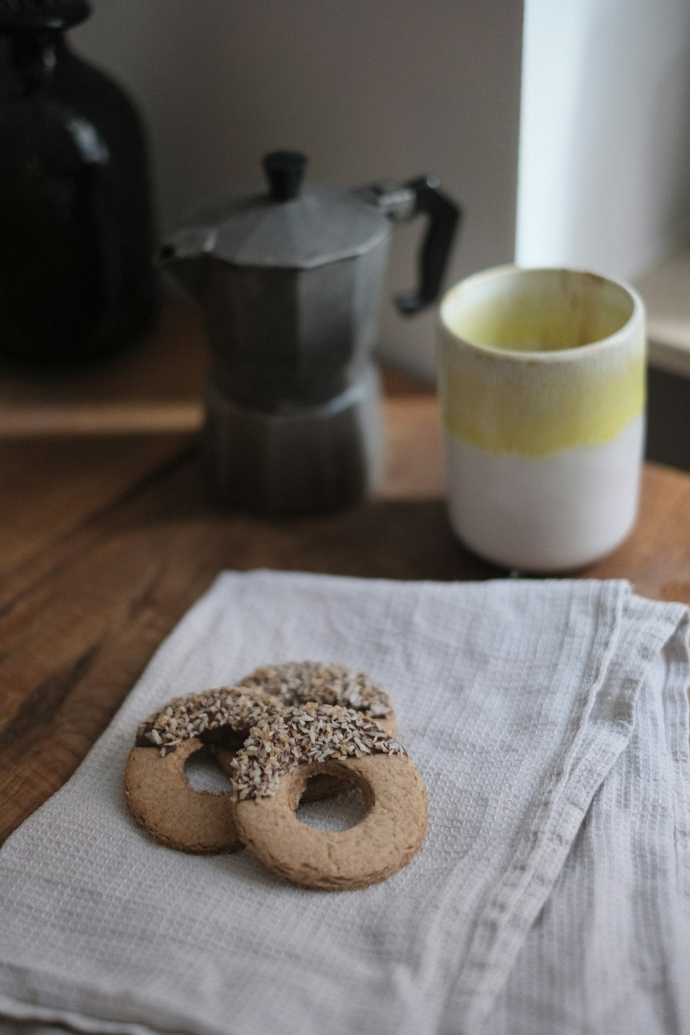 white ceramic mug beside brown doughnut on brown wooden table
