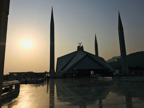 A peaceful mosque courtyard bathed in warm golden light during sunset.
