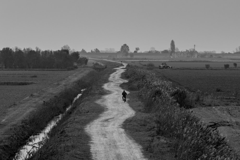 grayscale photo of person walking on dirt road