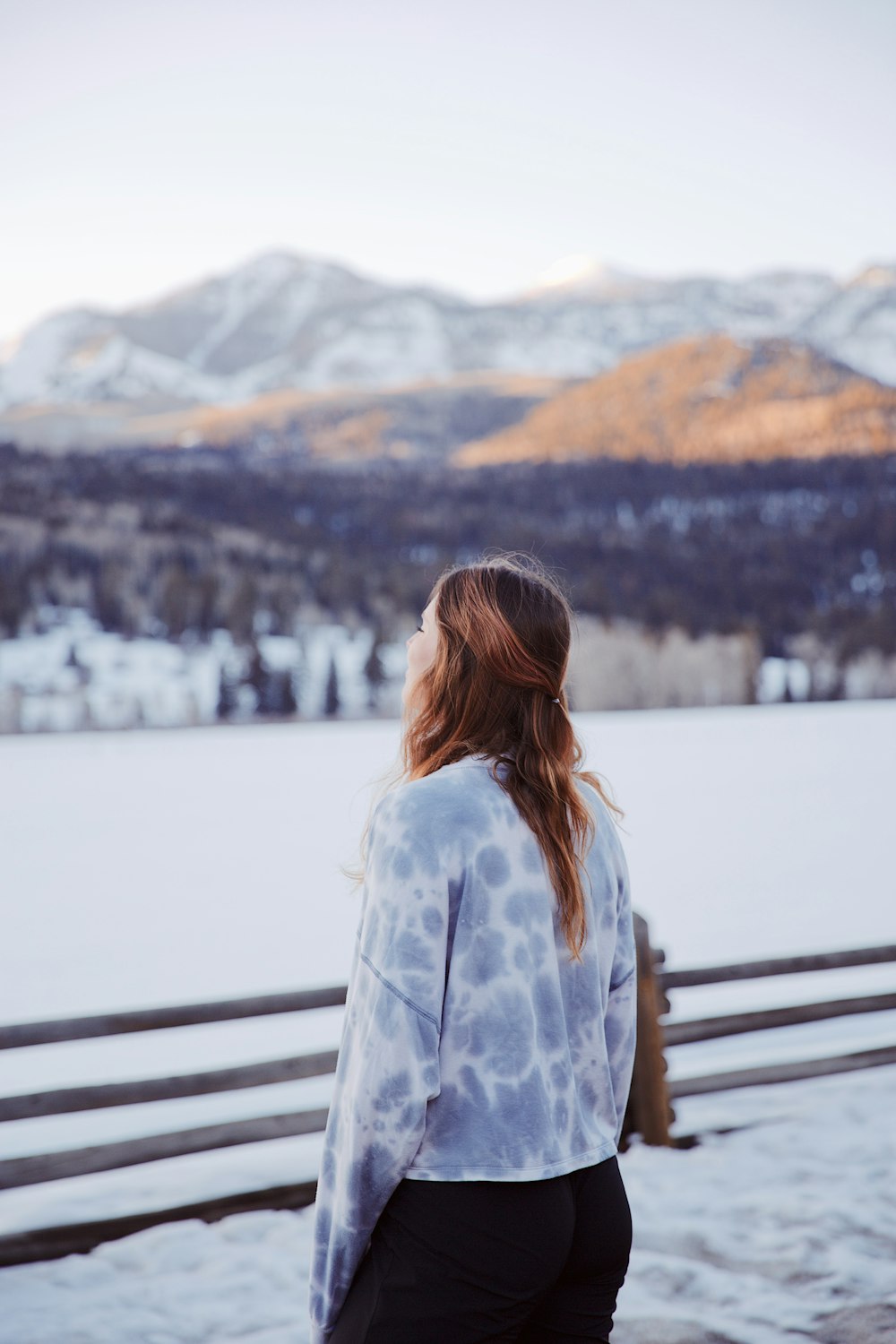 Una mujer parada frente a una montaña cubierta de nieve