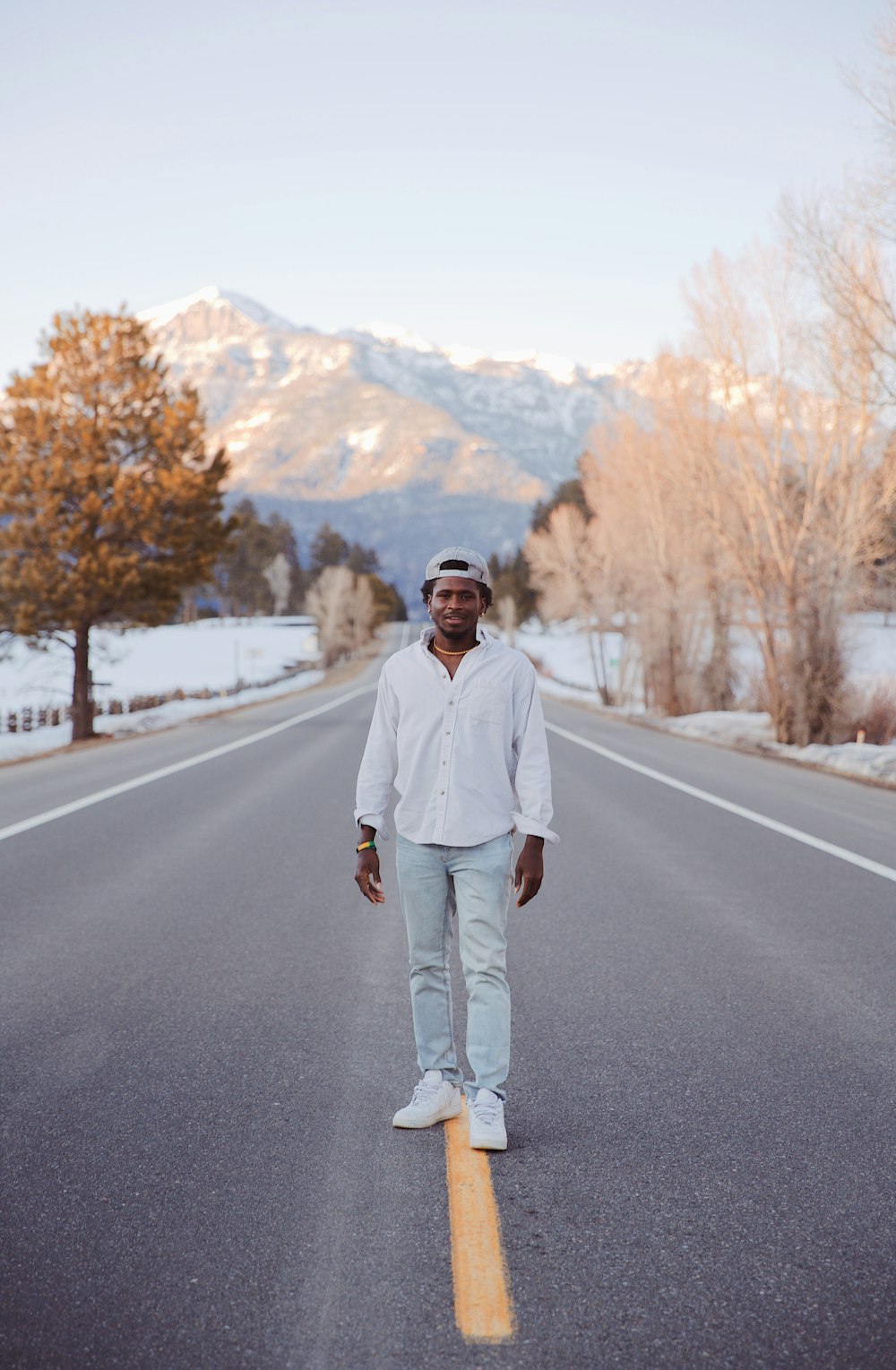 man in white dress shirt and gray pants standing on gray asphalt road during daytime