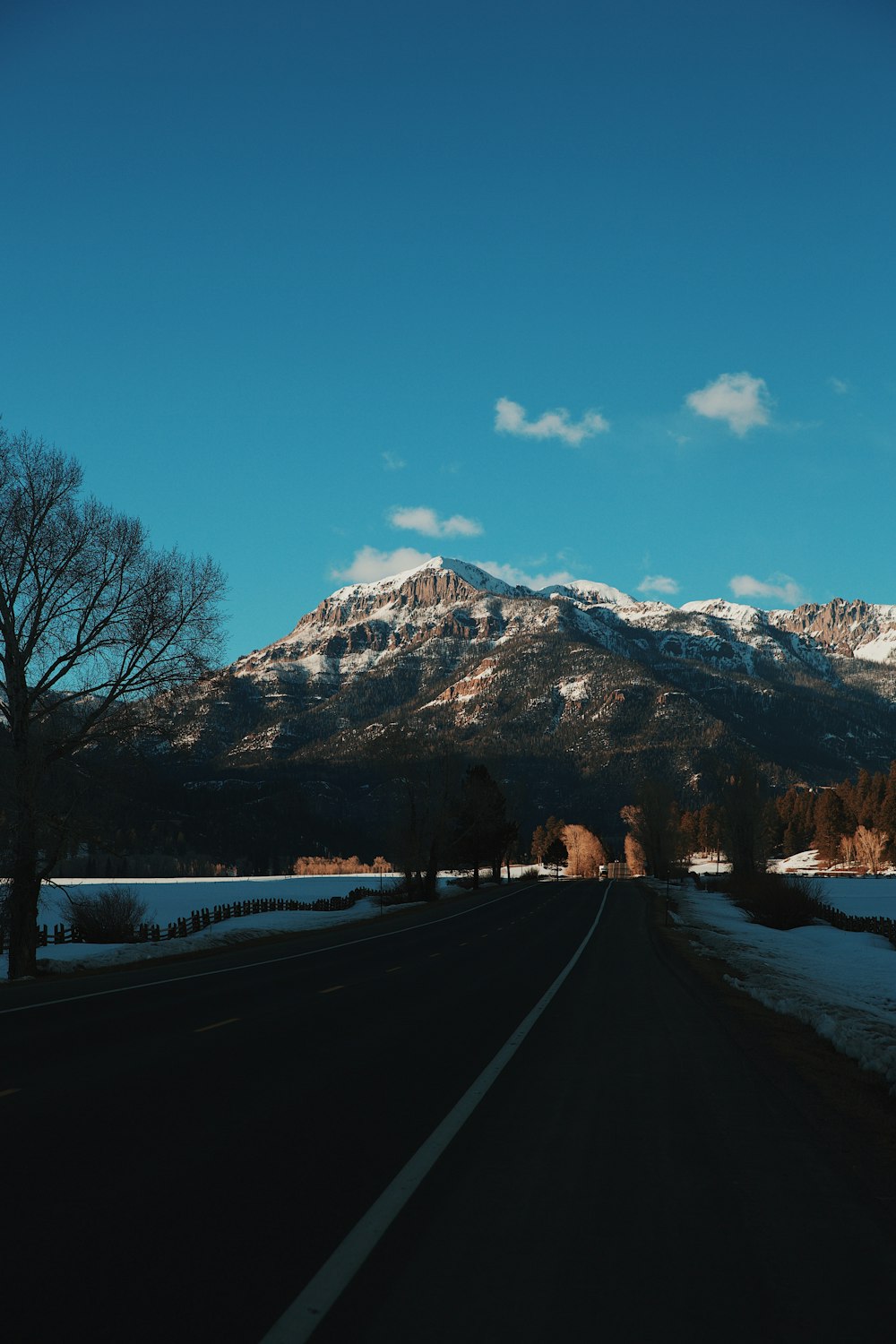 black asphalt road near snow covered mountain during daytime