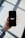 A hand holding a smartphone displaying the Uber logo on its screen. The background appears softly blurred, providing a contrast to the sharp focus on the phone. The hand is wearing a long-sleeved, checkered shirt.