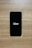 A smartphone with a black screen displays the Uber logo in white text. The phone is placed on a wooden surface with a light brown texture.