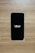 A smartphone with a black screen displays the Uber logo in white text. The phone is placed on a wooden surface with a light brown texture.