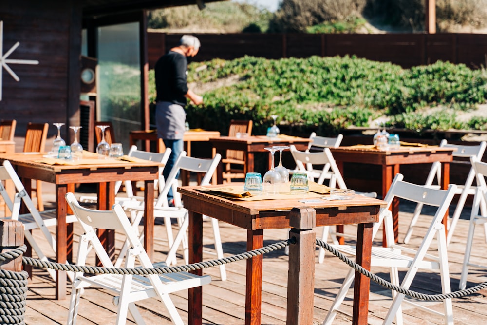 homme en t-shirt bleu debout à côté d’une table en bois marron pendant la journée