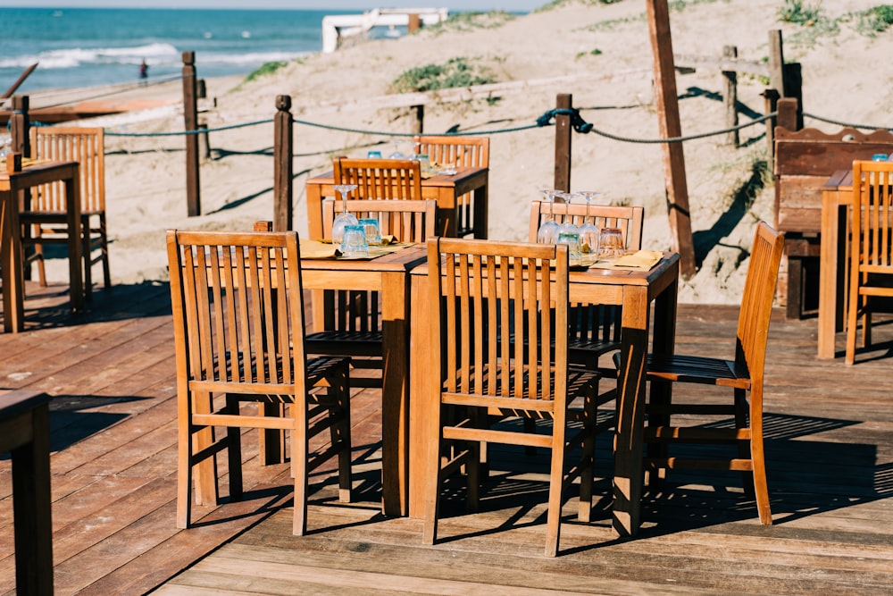 Mesa de madera marrón con sillas en la playa durante el día