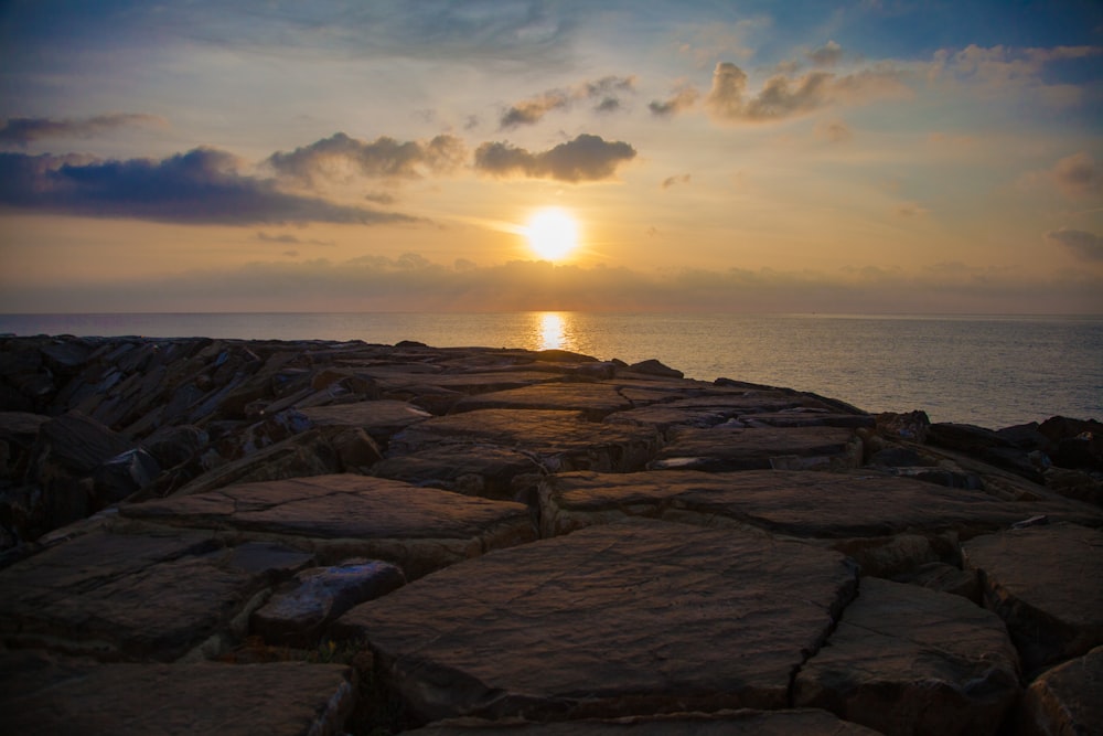 brown rocks near body of water during sunset