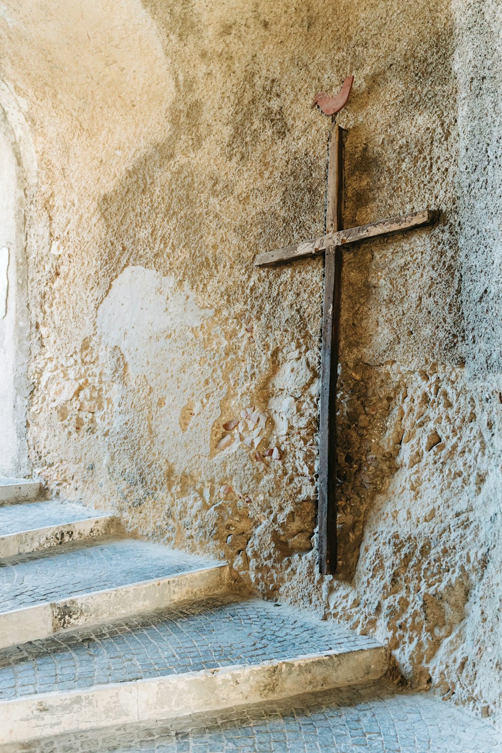 brown wooden cross on brown concrete wall