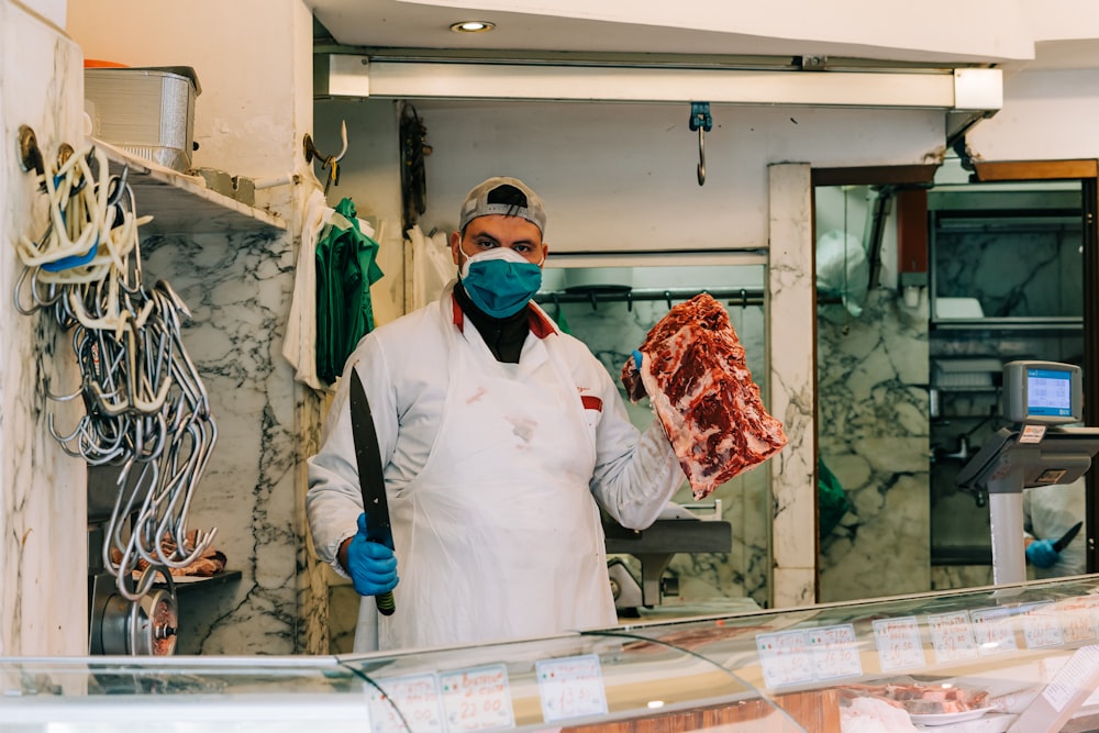 man in white dress shirt and black necktie holding raw meat