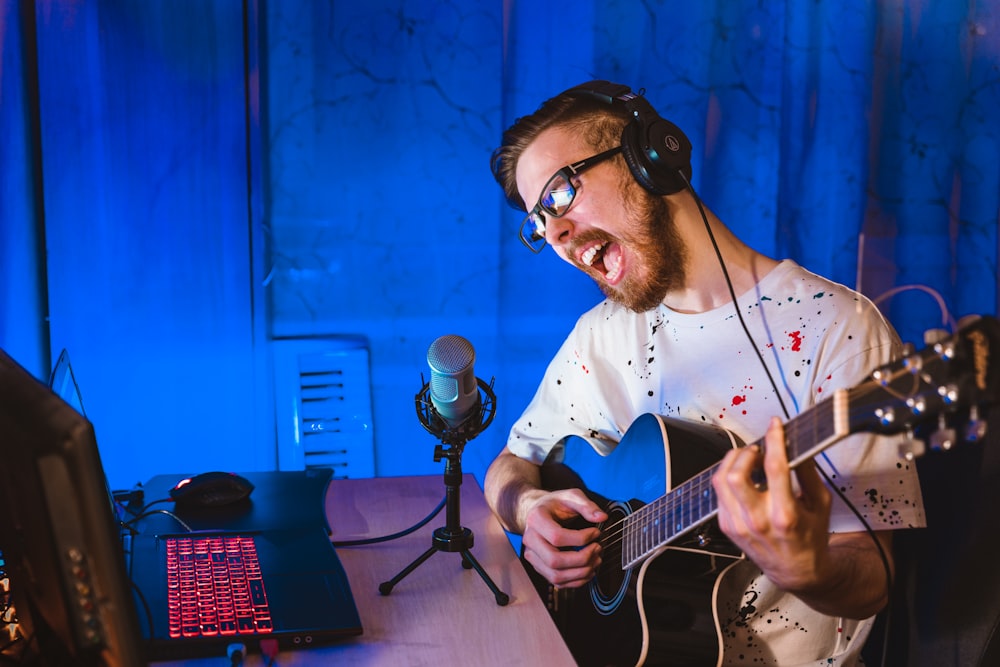 man in white and black plaid dress shirt playing guitar