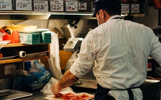 man in white dress shirt standing in front of raw meat