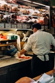 man in white dress shirt standing in front of raw meat