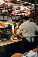 man in white dress shirt standing in front of raw meat