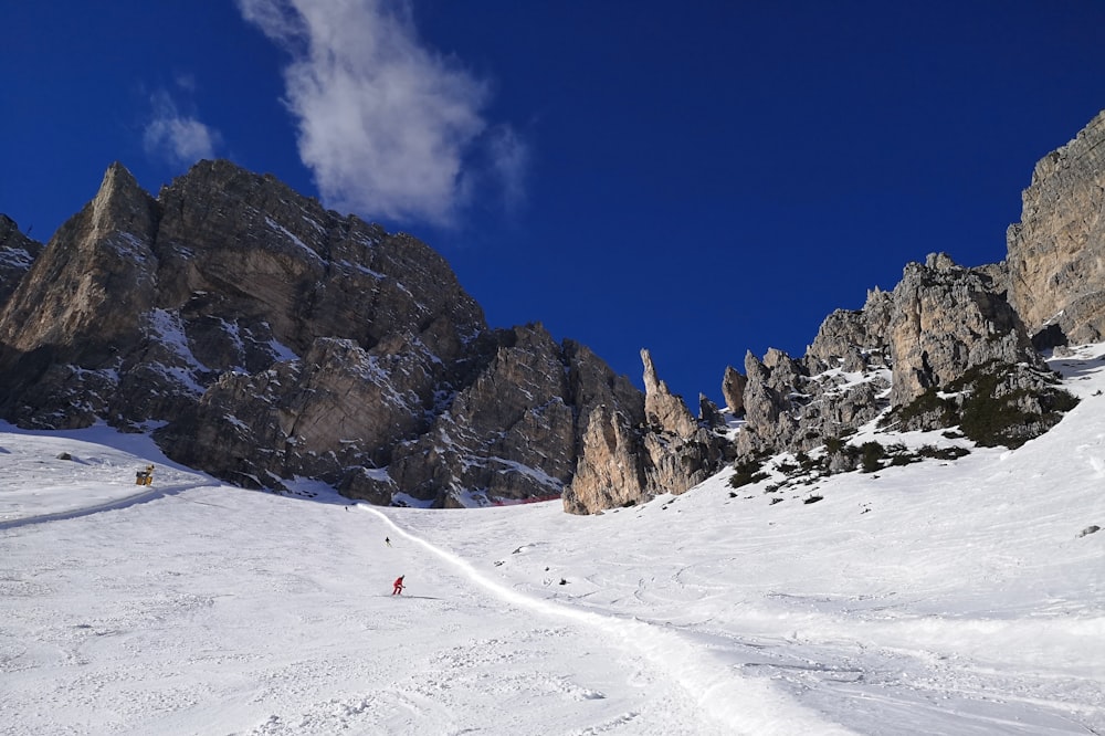 person in red jacket walking on snow covered field during daytime