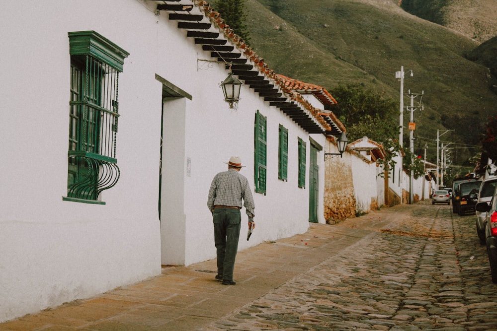 man in gray jacket and gray pants standing in front of white concrete house during daytime