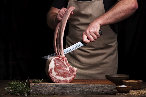 Chef slicing a gourmet tomahawk steak in a kitchen