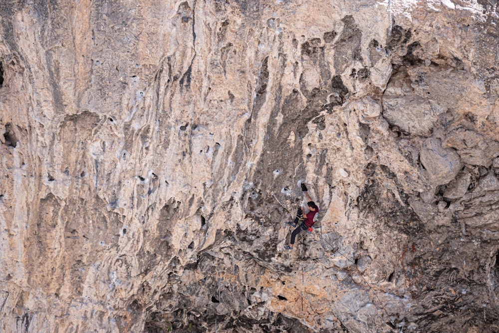 person climbing on brown rocky mountain during daytime