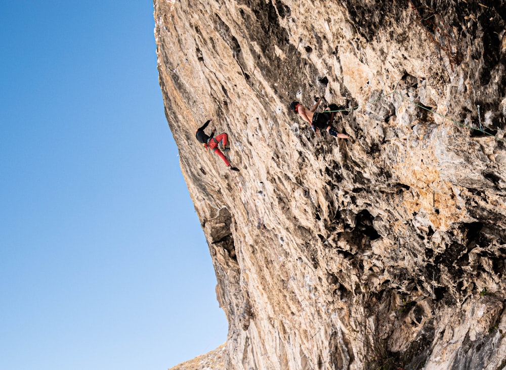 person in red shirt climbing on brown rock mountain during daytime