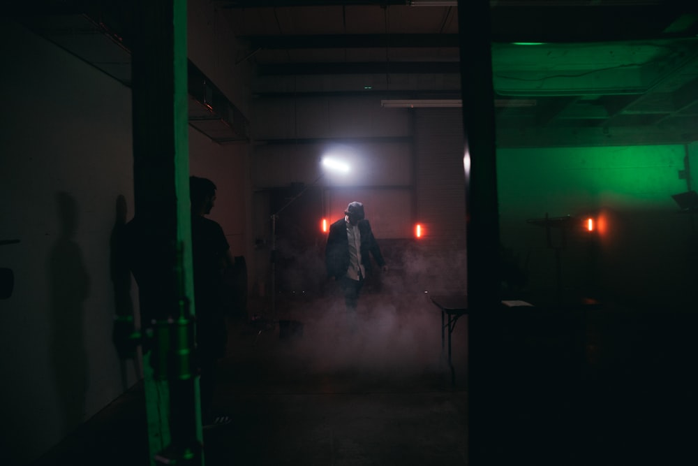 man in black jacket standing near green wall