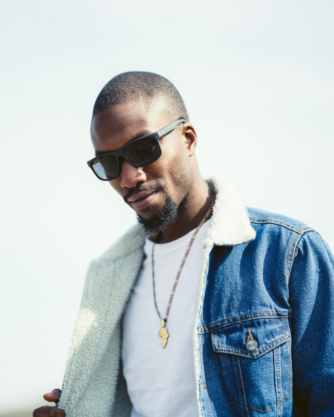 man in blue denim jacket wearing black sunglasses